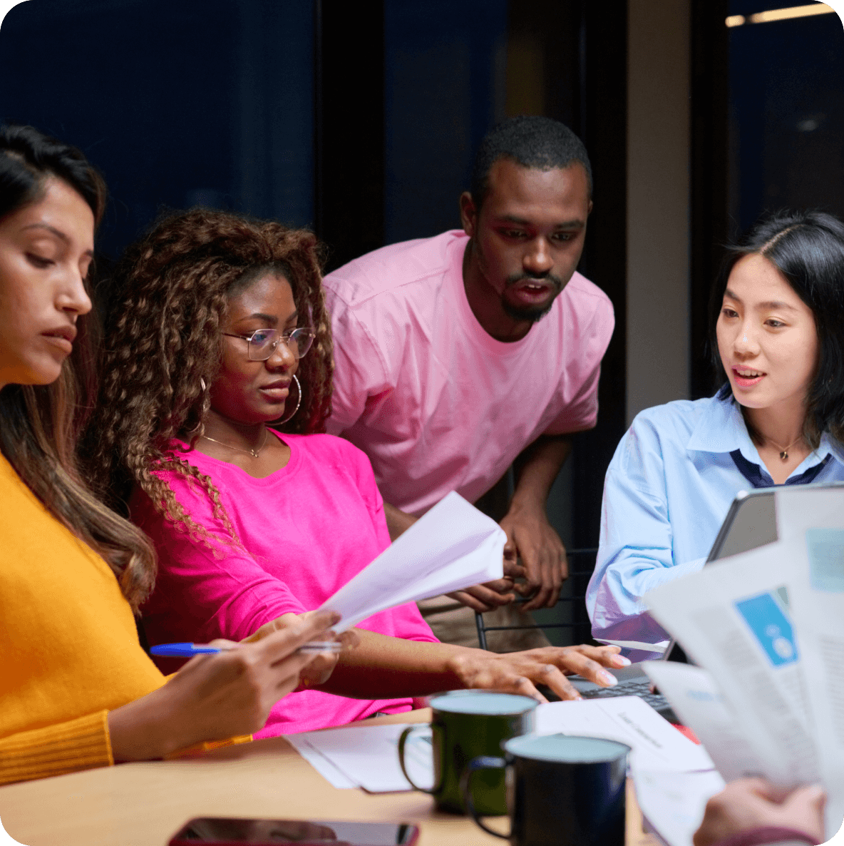 a group of people are sitting around a table looking at papers
