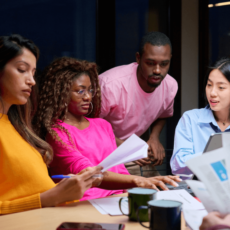 a group of people sitting around a table looking at papers