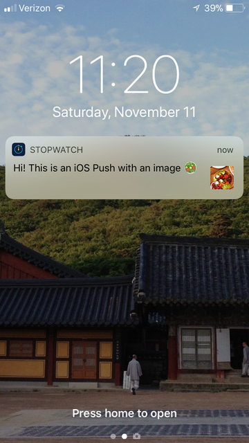 Notificação por push do iOS com texto que diz: "Oi! Este é um push do iOS com uma imagem" com um emoji. Há uma pequena imagem ao lado do texto.